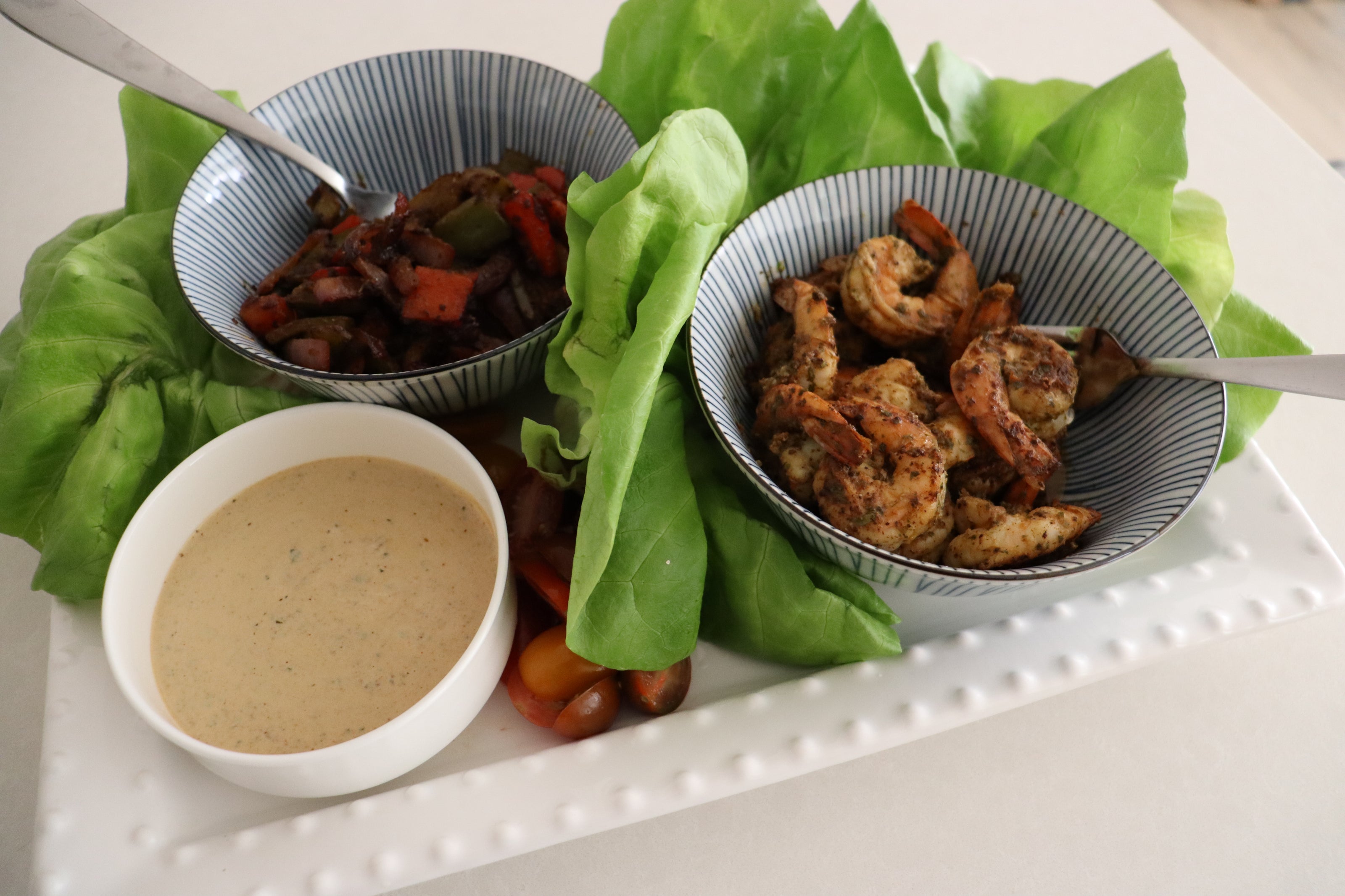 Plated dish with shrimp, vegetables, and a sauce on a white surface